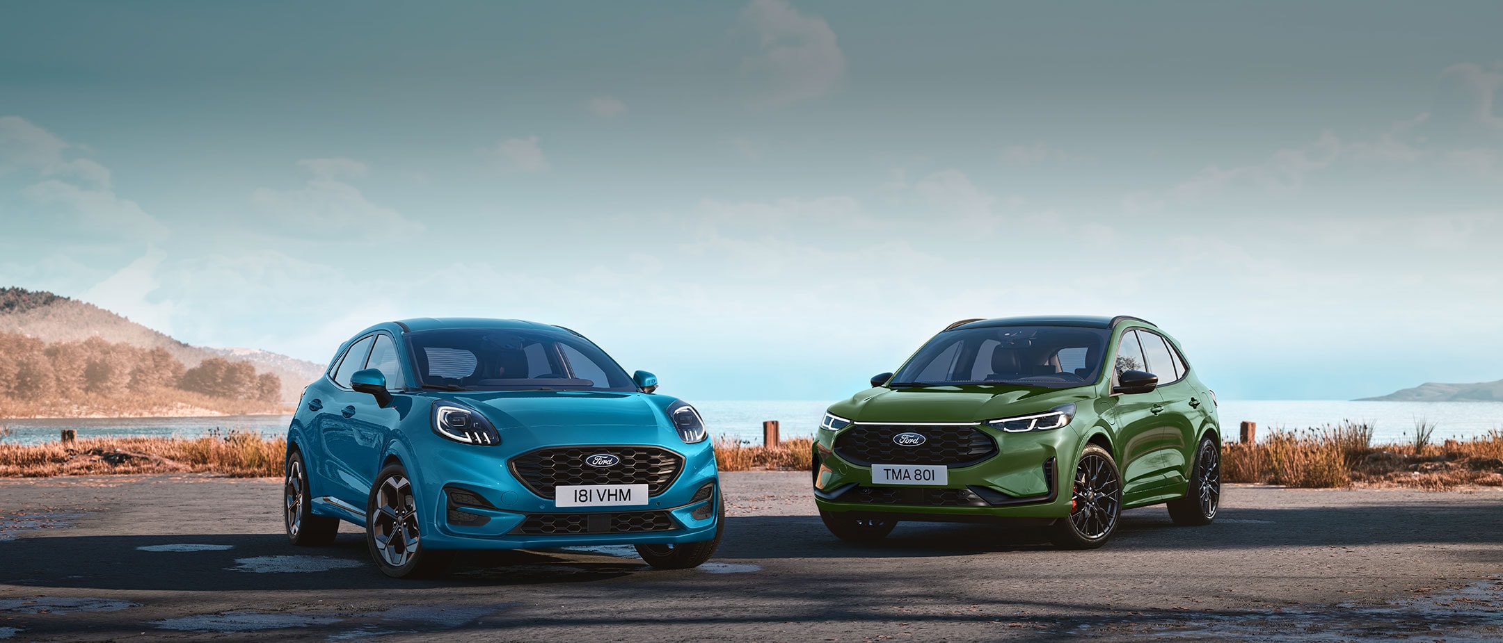 Niebieski Ford Puma oraz zielony Ford Kuga zaparkowane na nadbrzeżnej drodze na tle górskiego krajobrazu