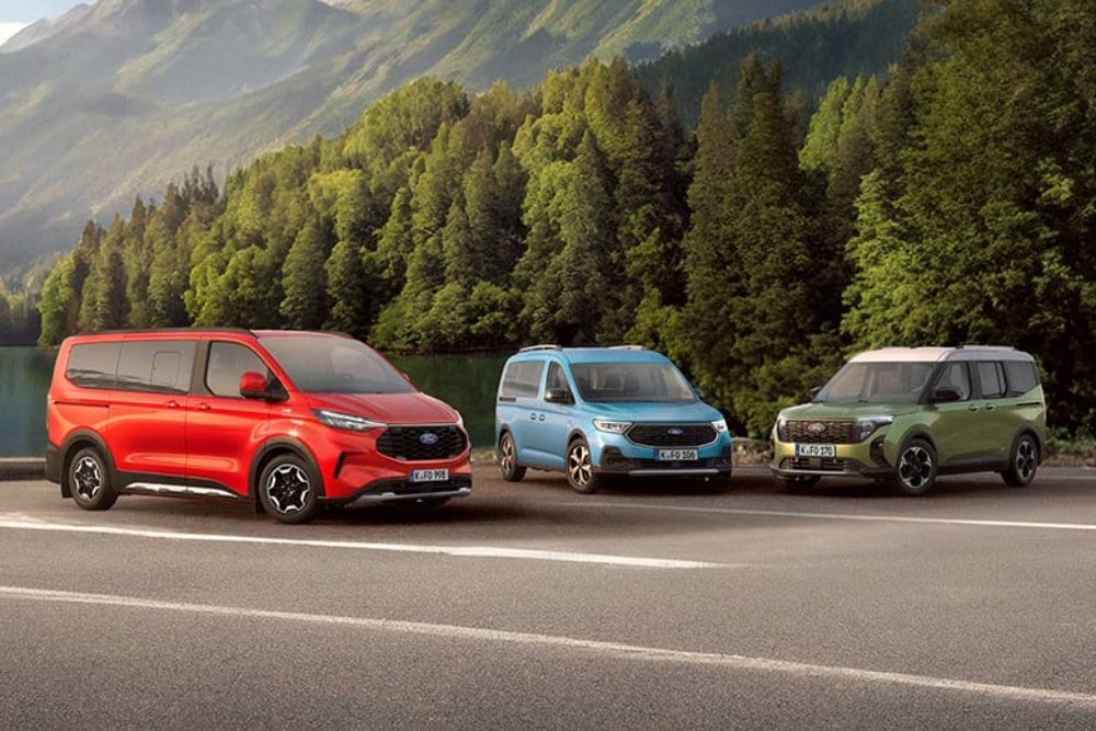 Czerwony Ford Tourneo Custom, niebieski Tourneo Connect i zielony Tourneo Courier przy jeziorze w górach.