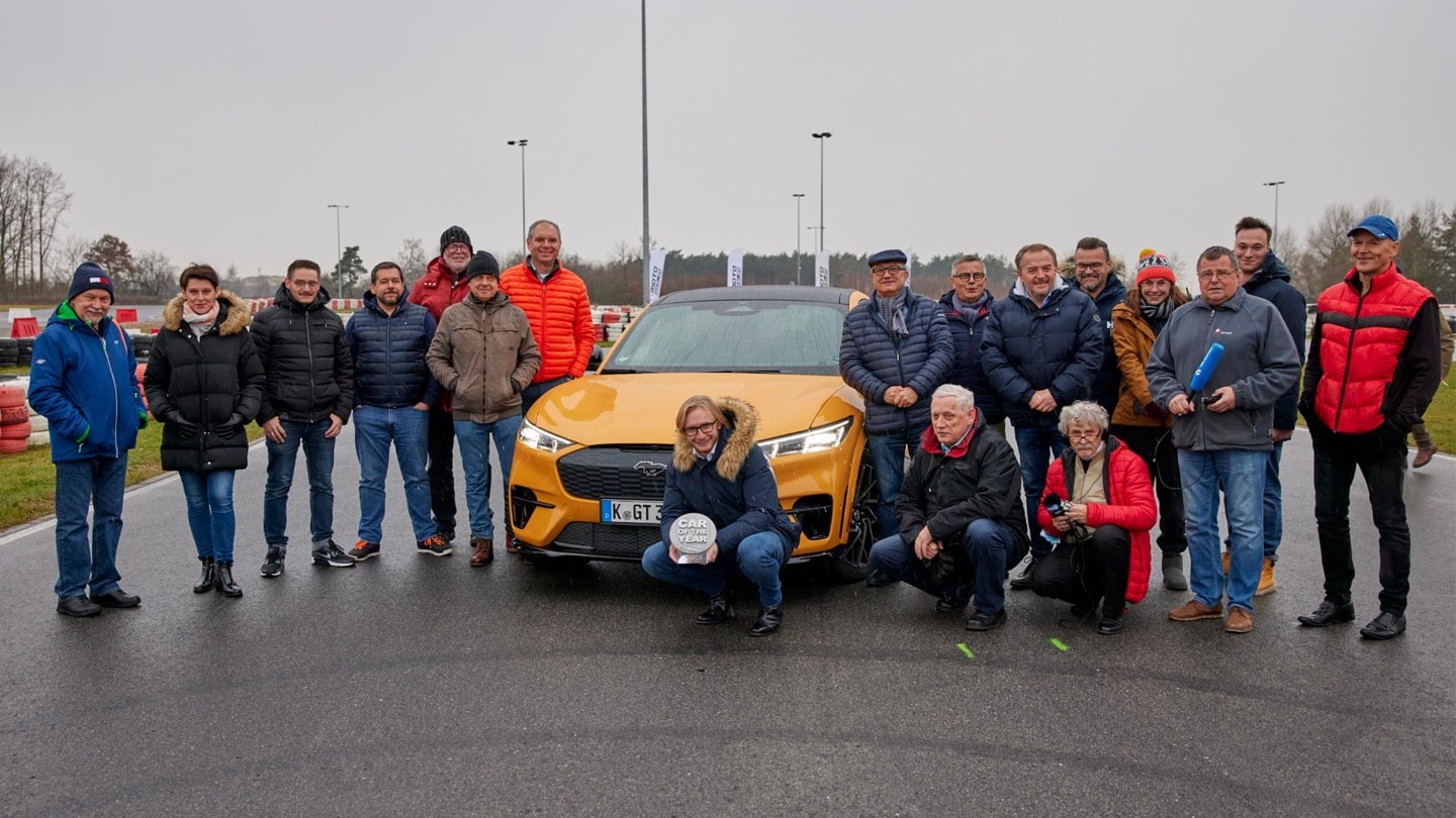 A group of people standing around a Mustang Mach-E