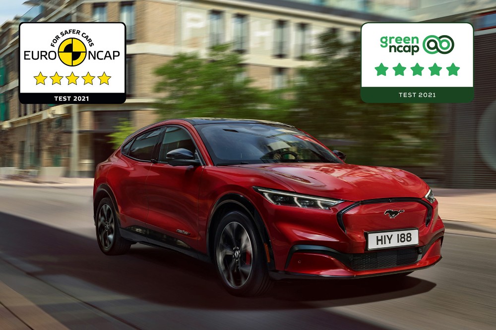 Czerwony Ford Mustang Mach-E jadący ulicą oraz logotypy nagród testów bezpieczeństwa NCAP.