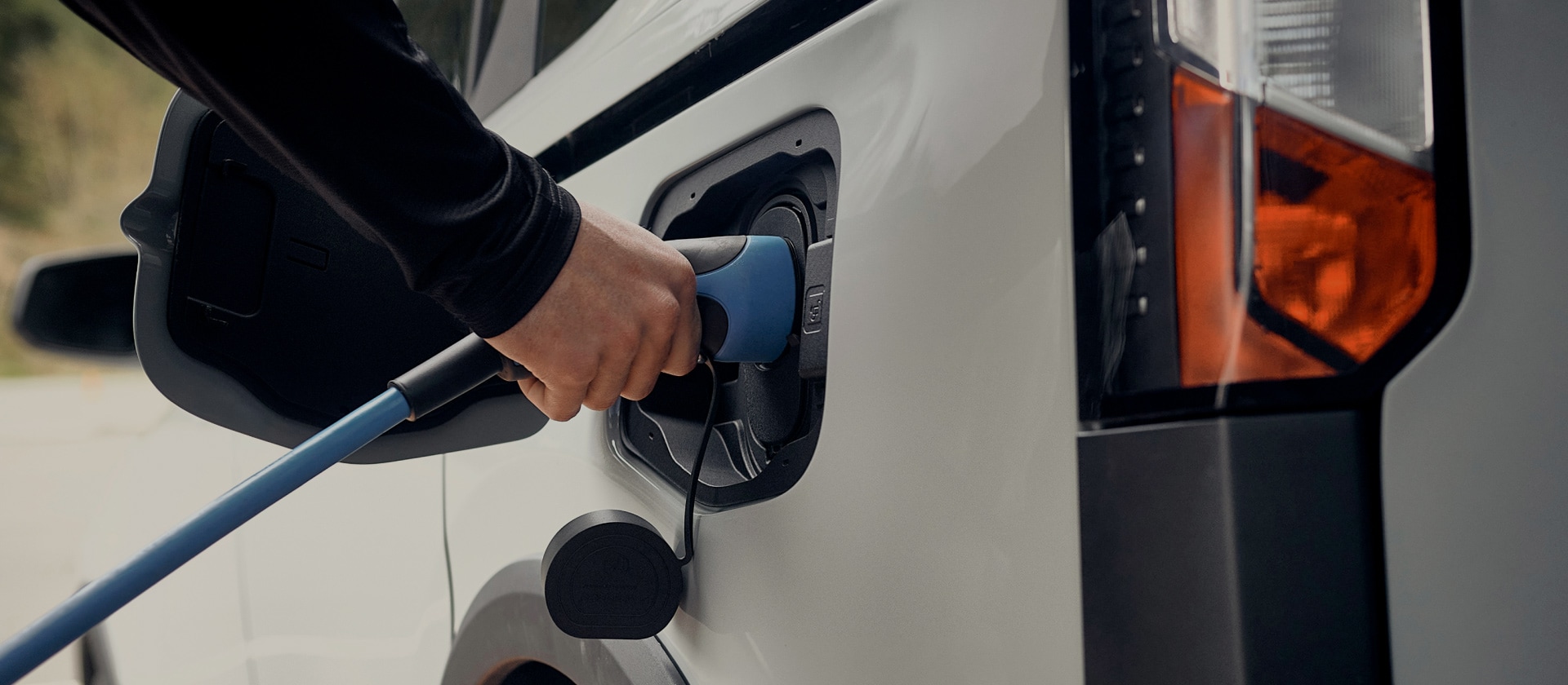 Zbliżenie na białego elektrycznego Forda, podłączanego do ładowarki.
