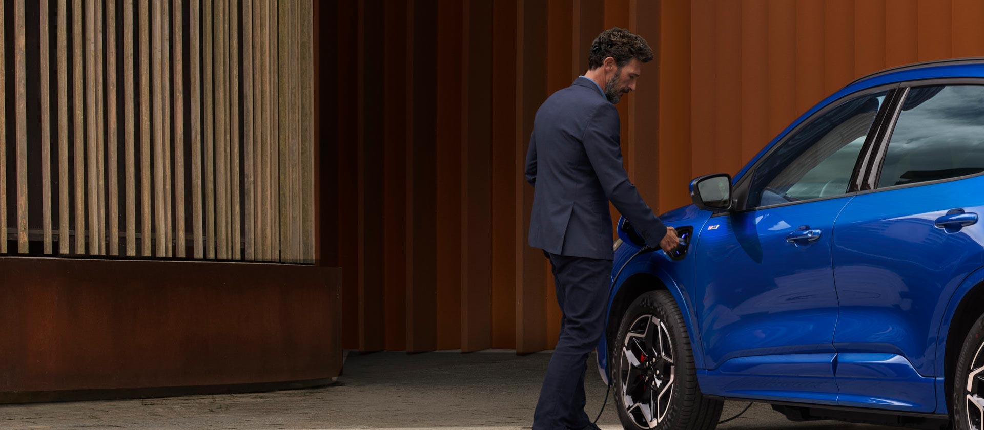 Osoba podłączająca samochód Forda plug-in hybrid do domowego kabla ładowania.