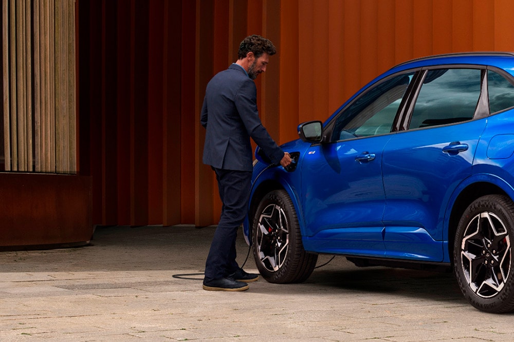 Osoba podłączająca kabel ładowania do samochodu Ford plug-in hybrid.