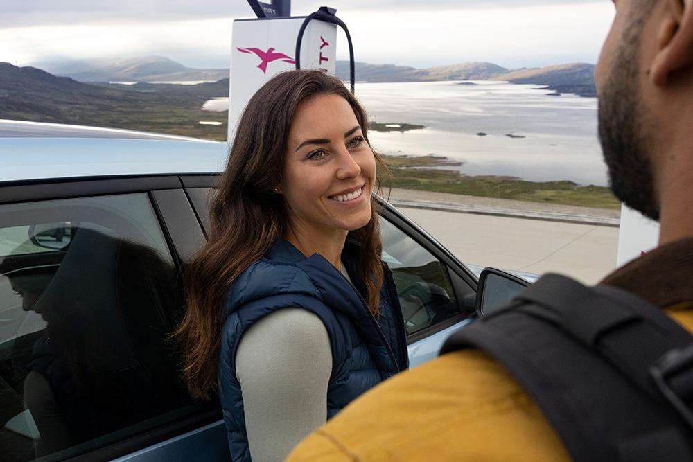 Two people chatting while charging an electric Ford Explorer at an IONITY EV charging station.