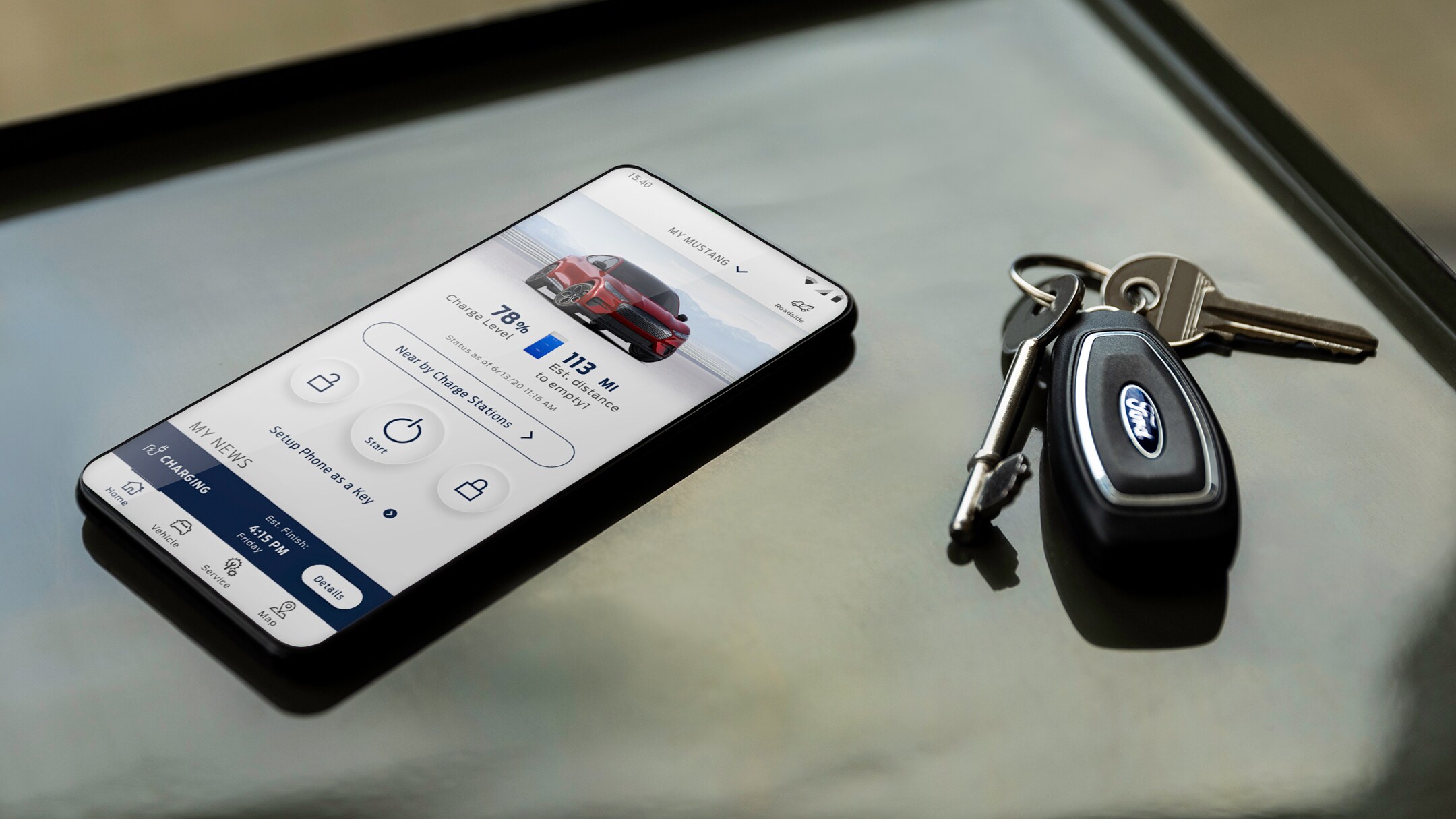 A phone showing the FordPass App on its screen sitting on a desk next to some car keys.