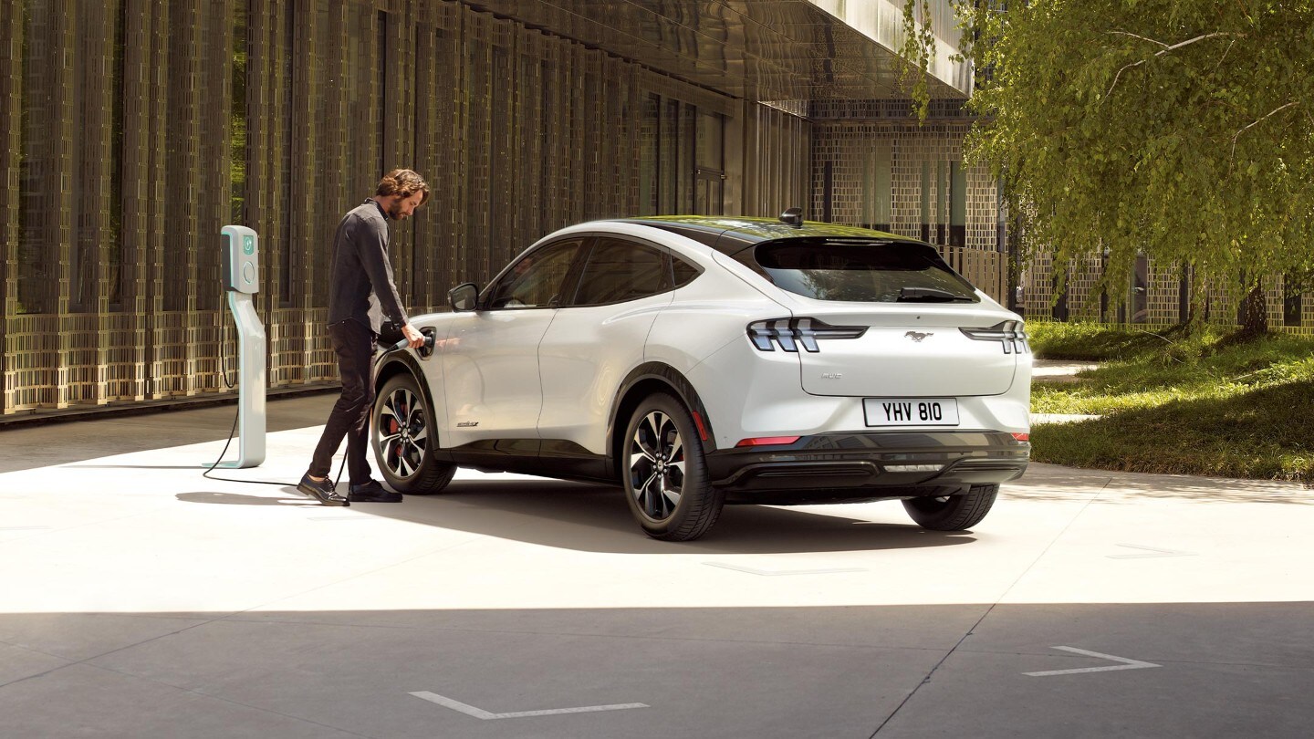 A man charging an all-new Ford Mustang Mach-E