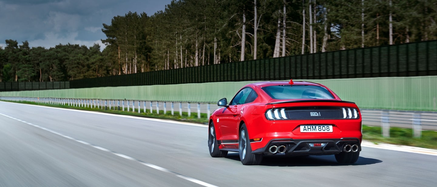 Ford Mustang Mach 1 driving on a race track rear view 