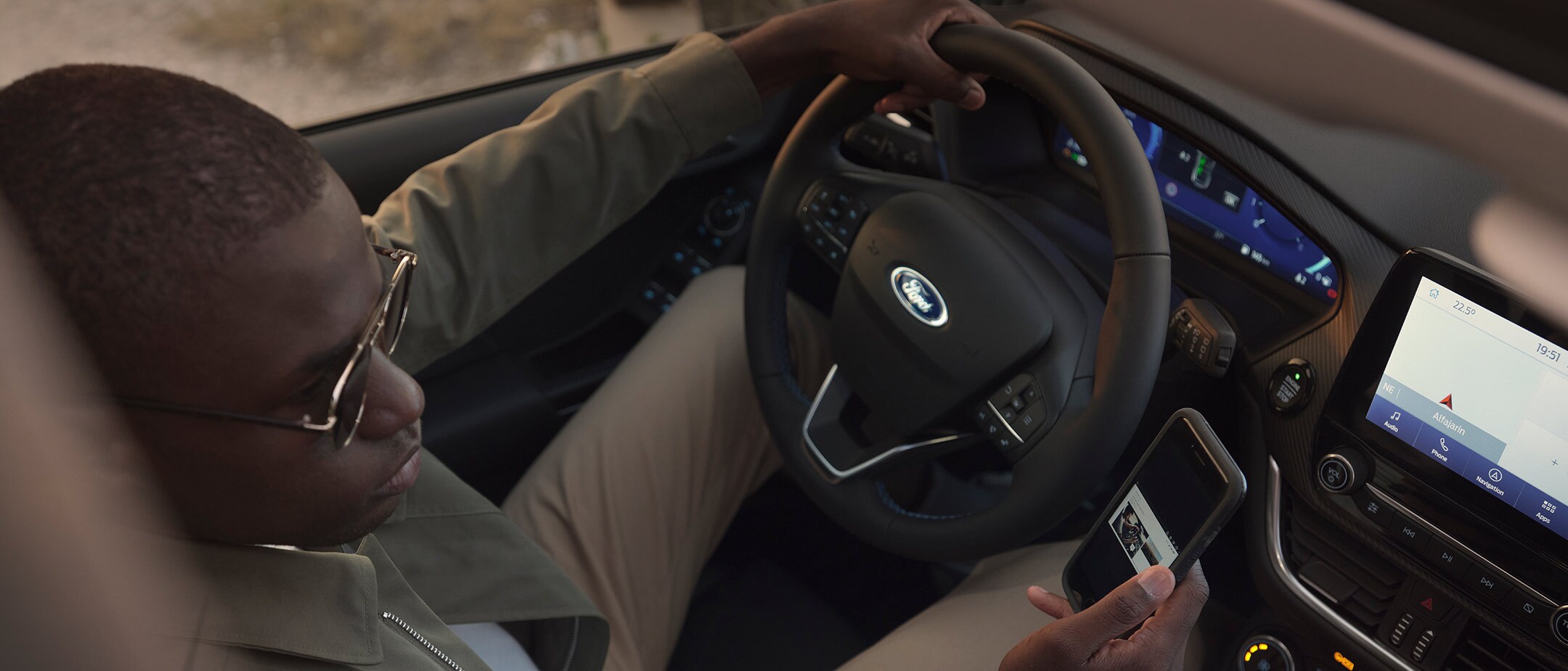 Driver sitting behind the wheel of a Fiesta, looking at a smartphone