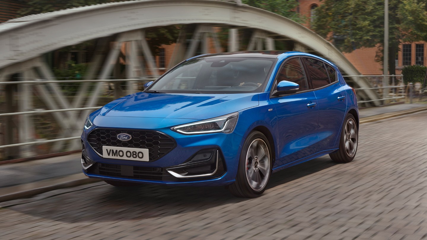 Front three quarter view of a blue Ford Focus driving on a road