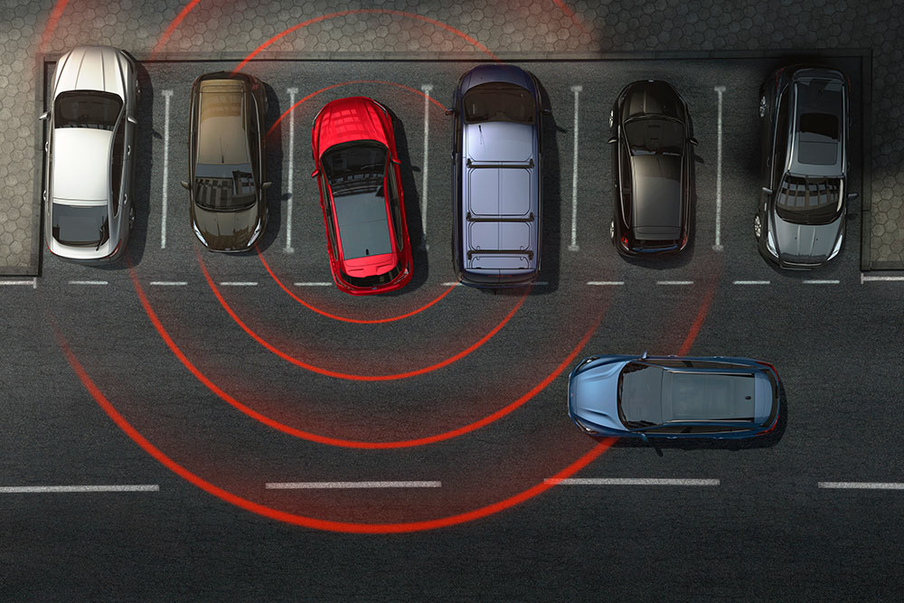 Grafika przedstawiająca samochód marki Ford cofający z miejsca parkingowego z aktywnym systemem ostrzegania o ruchu poprzecznym (Cross Traffic Alert).