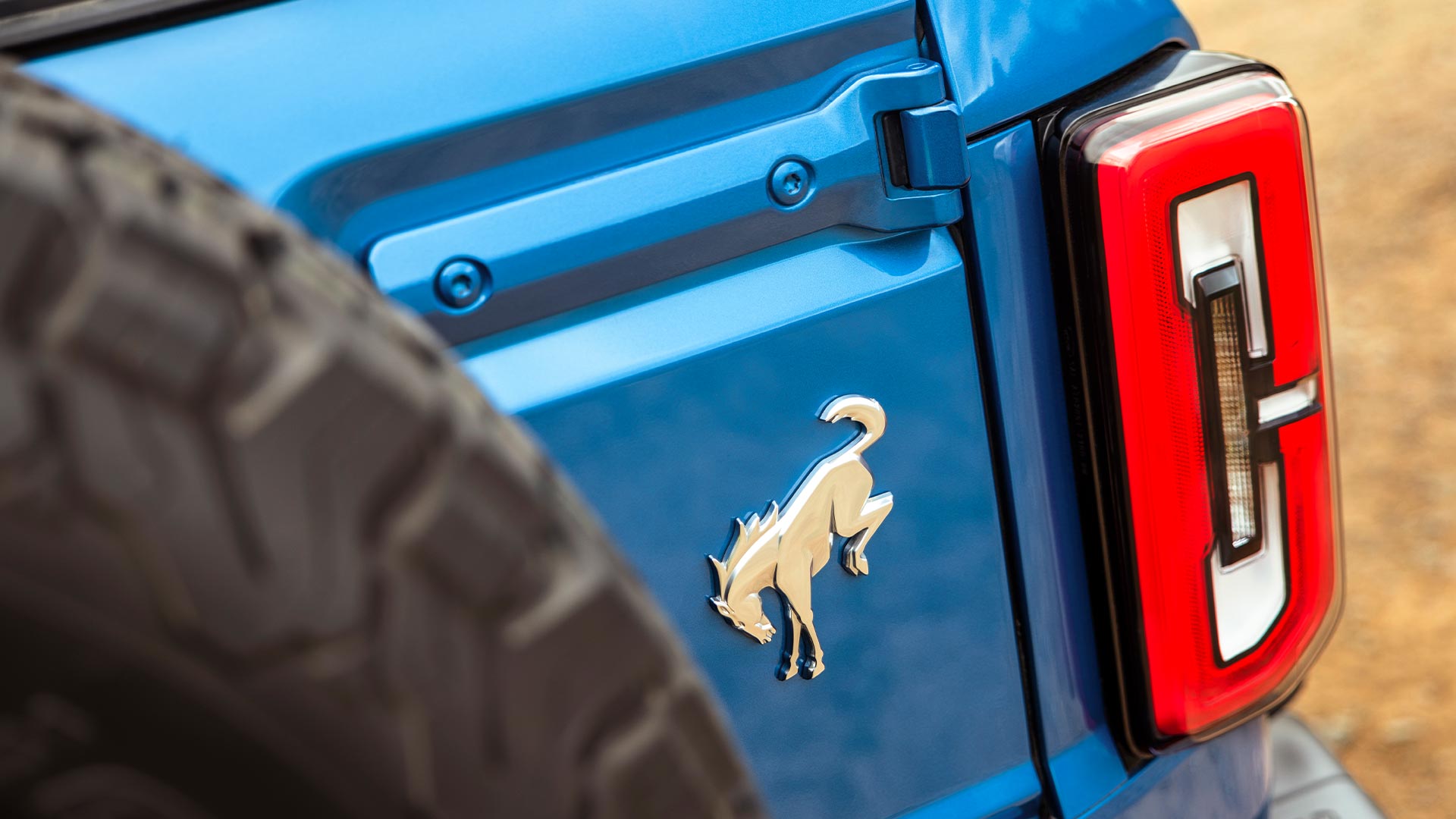 Zbliżenie na detale z oznaczeniami marki z tyłu niebieskiego Forda Bronco.