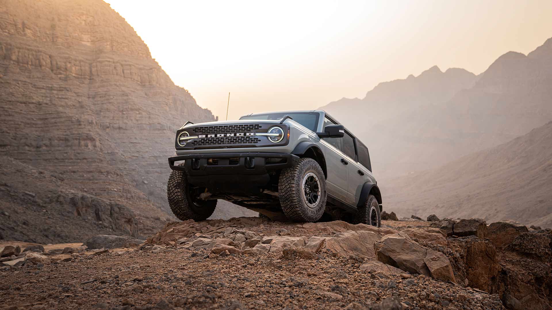 Szary Ford Bronco zaparkowany na skalistej ścieżce w górzystym krajobrazie.