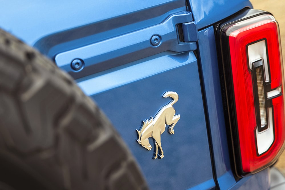 Zbliżenie na detale z oznaczeniami marki z tyłu niebieskiego Forda Bronco.