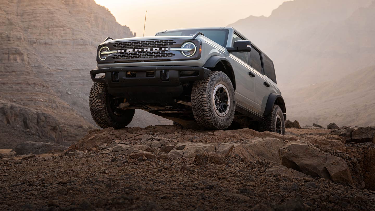 Szary Ford Bronco zaparkowany na skalistej ścieżce w górzystym krajobrazie.