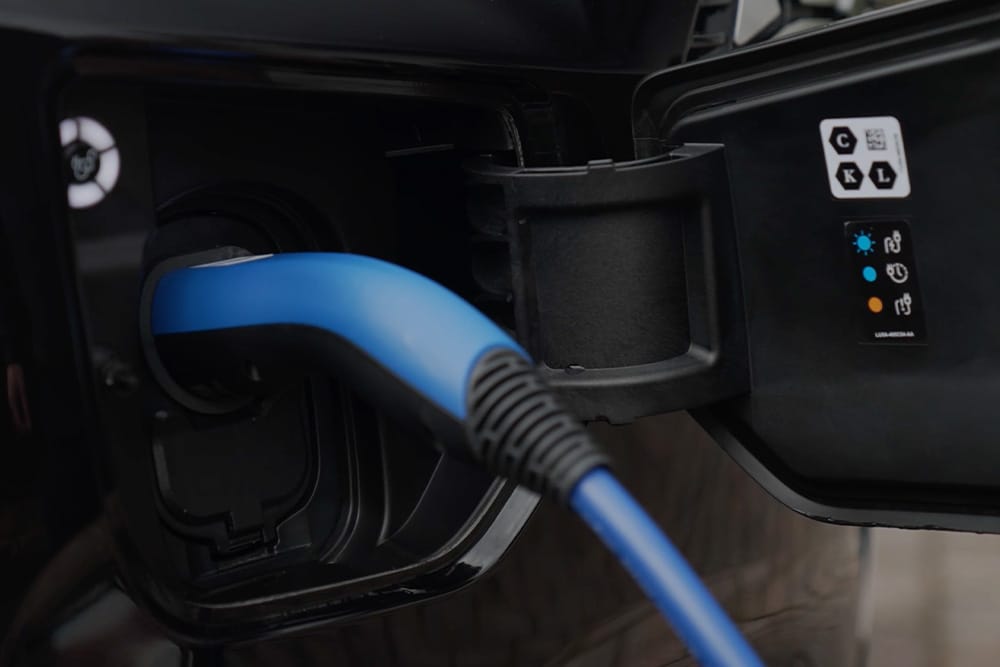 Zbliżenie na niebieski kabel ładowania podłączony do gniazda ładowania pojazdu elektrycznego.