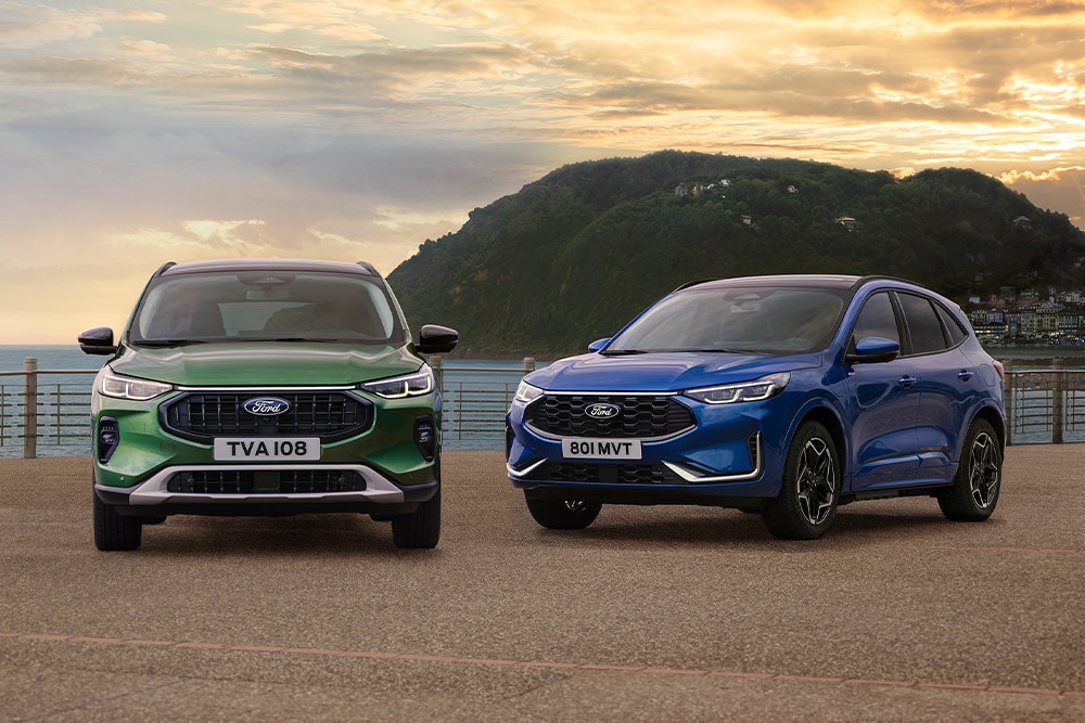 Zielony Ford Kuga Active i niebieski Ford Kuga ST Line zaparkowane obok siebie na nadmorskim parkingu. 