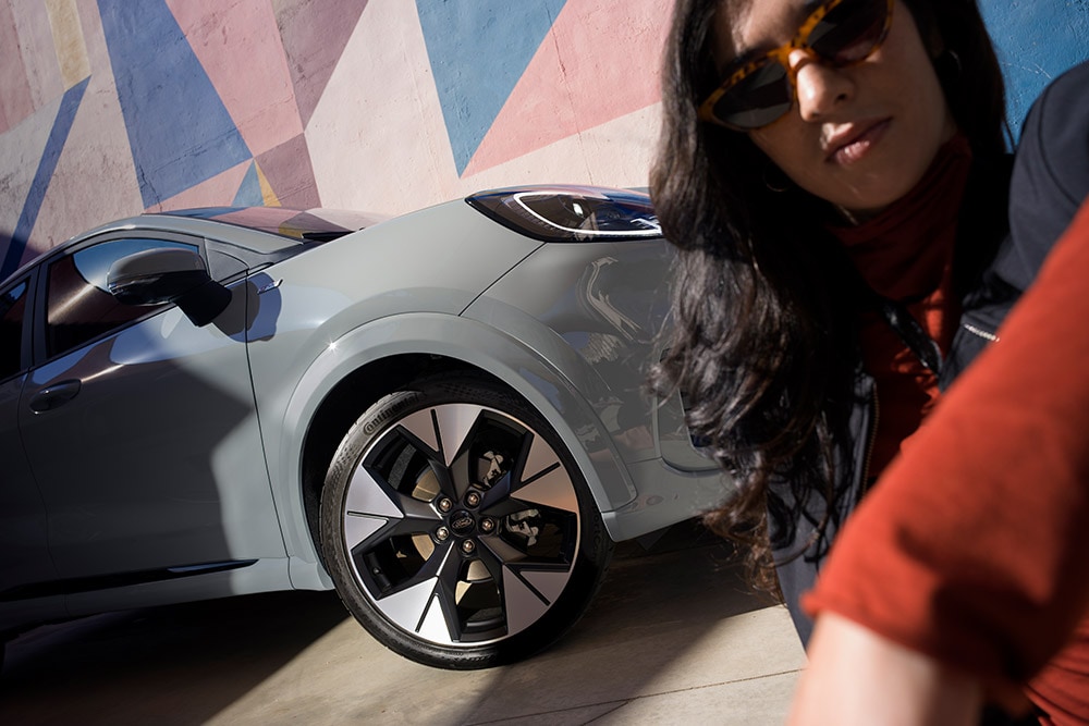 Zbliżenie na osobę obok szarego Forda Puma® z benzynowym silnikiem EcoBoost®.