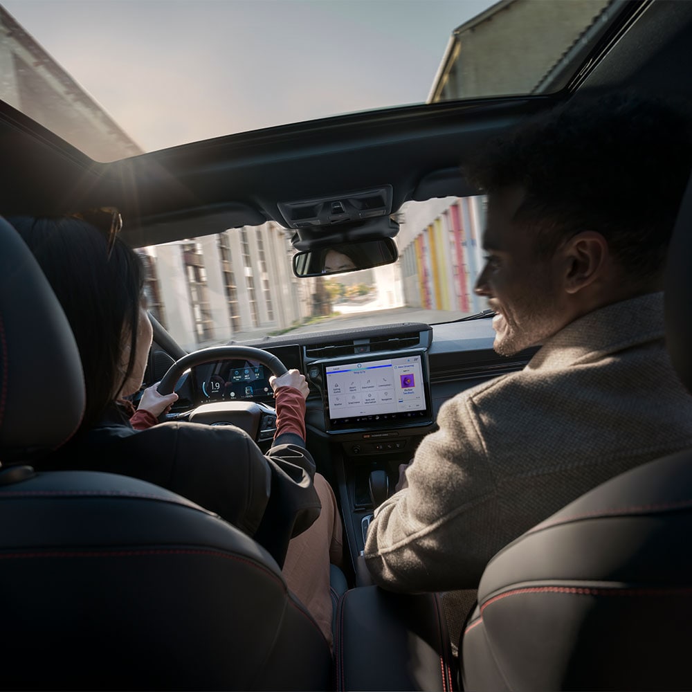 Kierowca i pasażer rozmawiają podczas jazdy po mieście w słoneczny dzień.