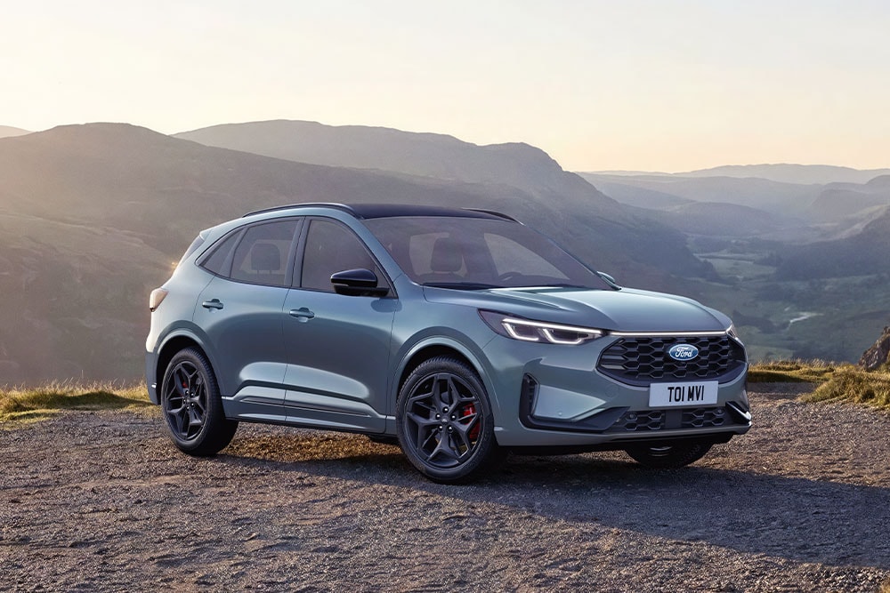 Szary Ford Kuga zaparkowany na żwirowej górskiej drodze o zachodzie słońca.