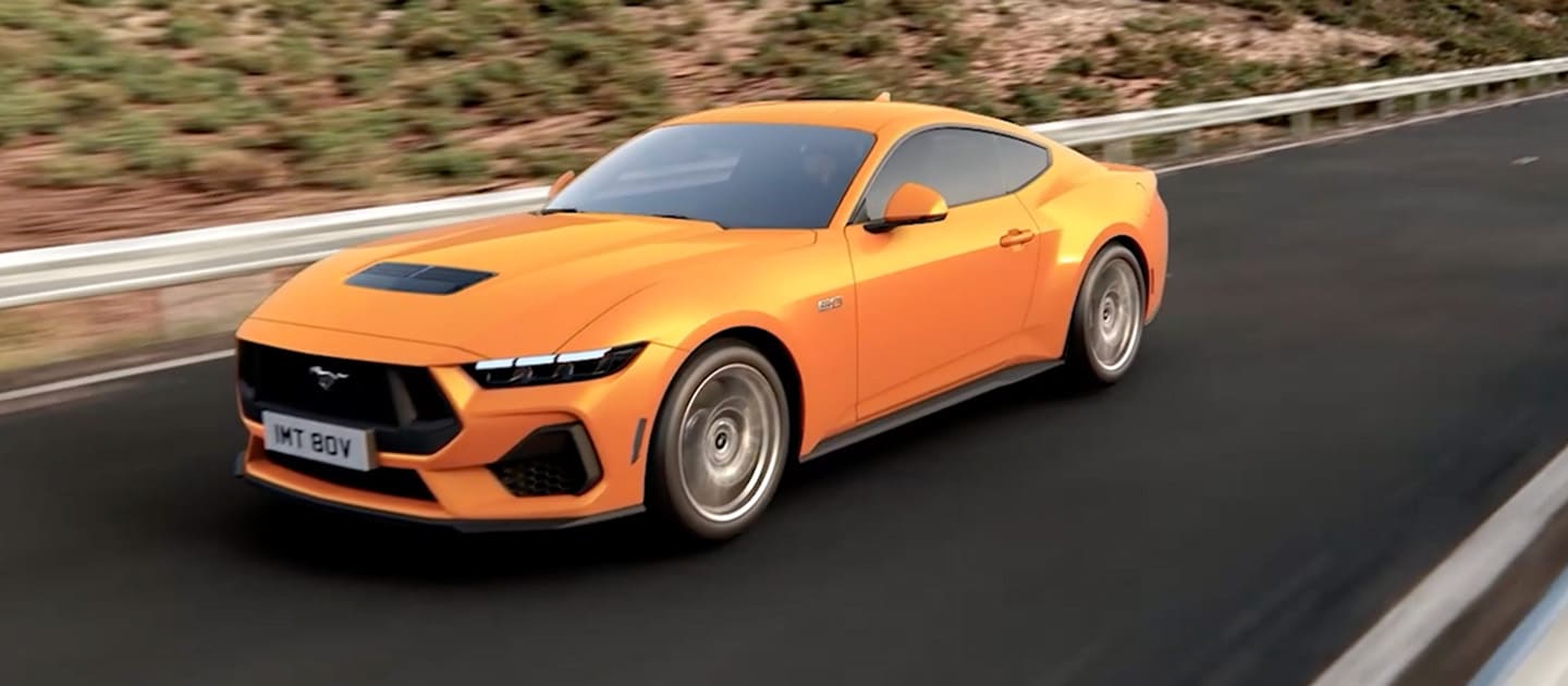 Ford Mustang GT Fastback w kolorze Orange Fury jadący po górskiej drodze
