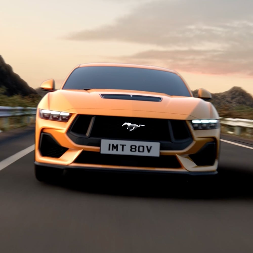 Widok od przodu pomarańczowego Ford Mustang z ujęciem z bliska reflektorów, grilla i znaczka Mustang