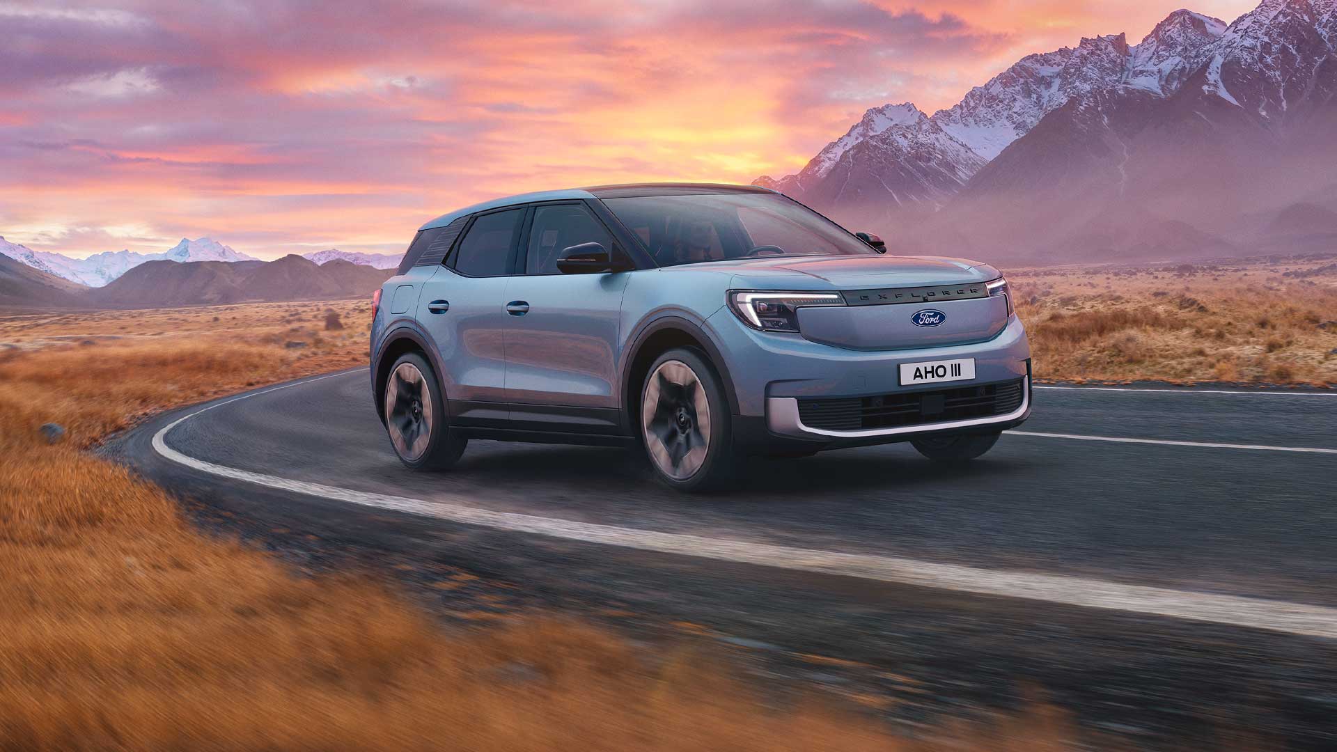 Nowy, elektryczny Ford Explorer® jedzie górską drogą o zachodzie słońca.