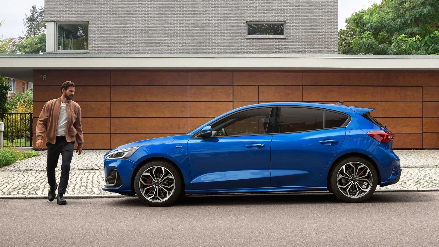 Man approaching a parked blue Ford Focus