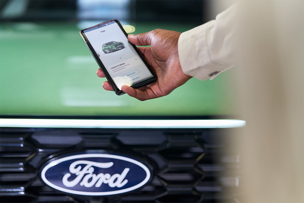 Mężczyzna patrzący na smartfon z wyświetloną aplikacją Ford