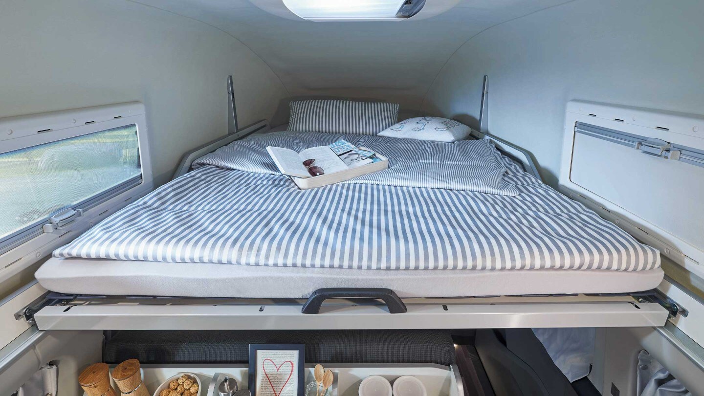 Woman siting and reading in Ford Transit Custom Nugget interior with lifted roof