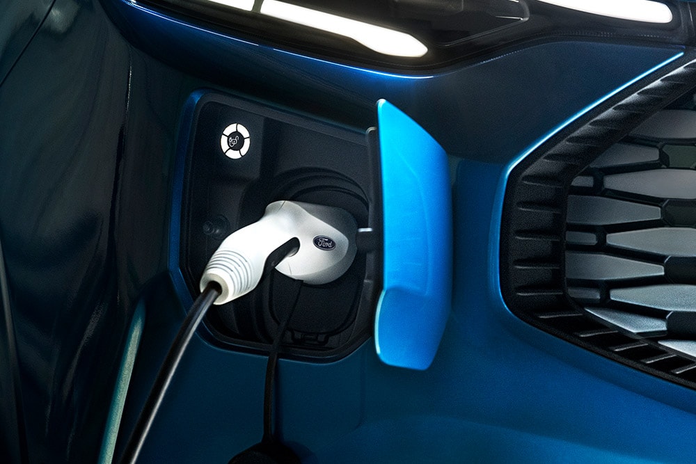 Niebieski Ford Transit Custom Plug-in Hybrid w trakcie ładowania.
