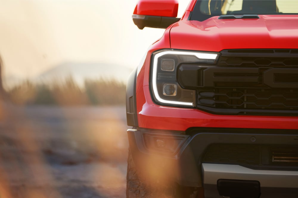 Zbliżenie na przedni grill czerwonego samochodu Ford Ranger Raptor.