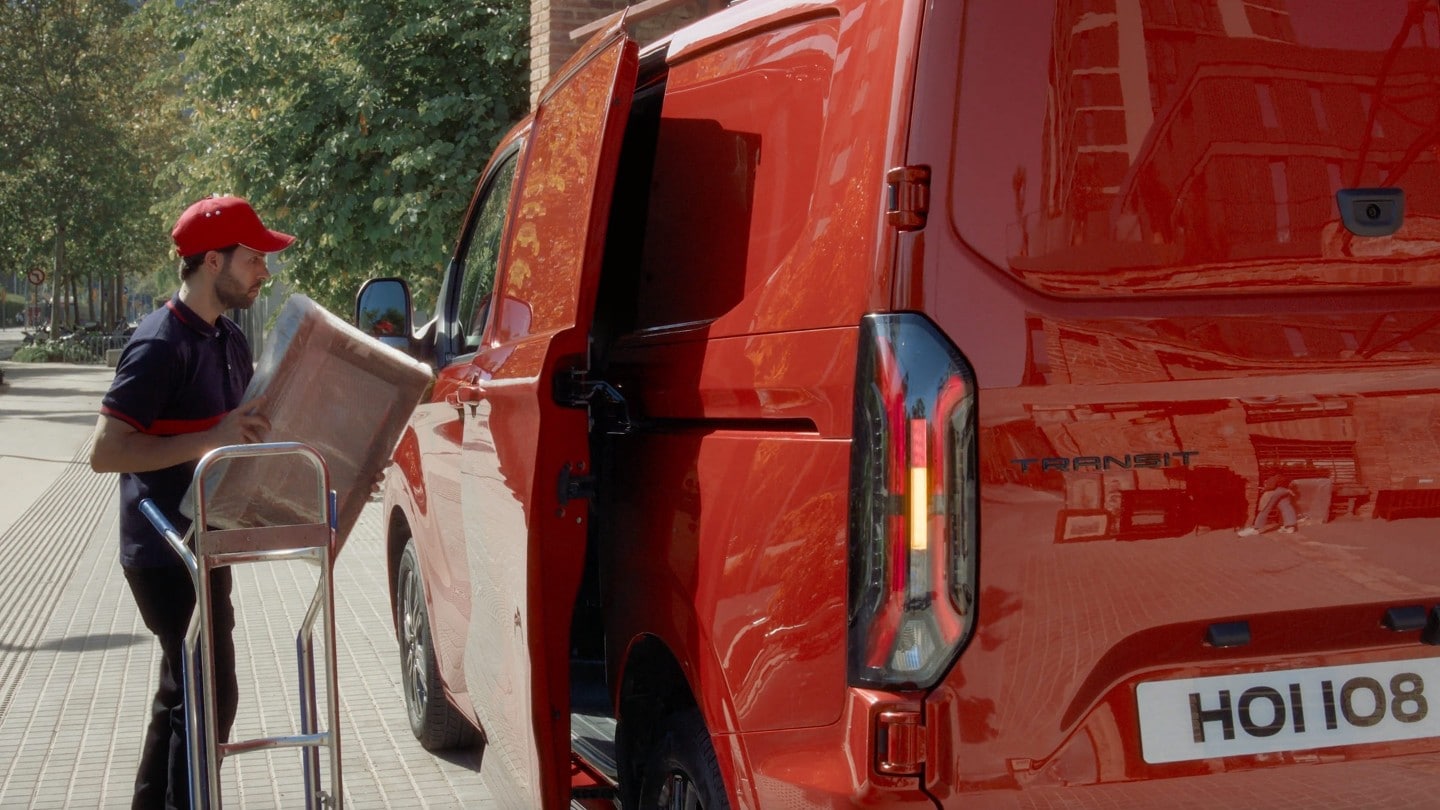 Kurier wkłada paczkę do zaparkowanego Transita Custom Limited