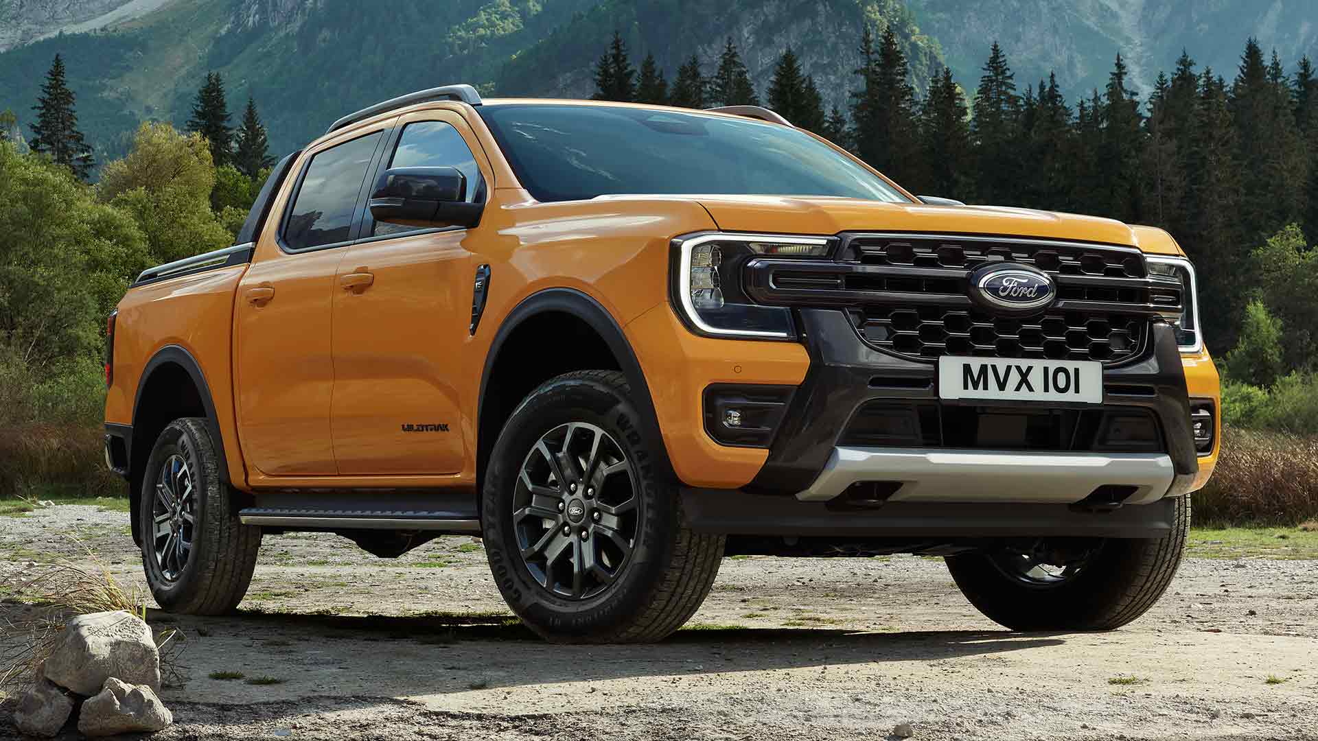Żółty Ford Ranger Wildtrak z podwójną kabiną na tle malowniczego leśnego i górskiego krajobrazu.
