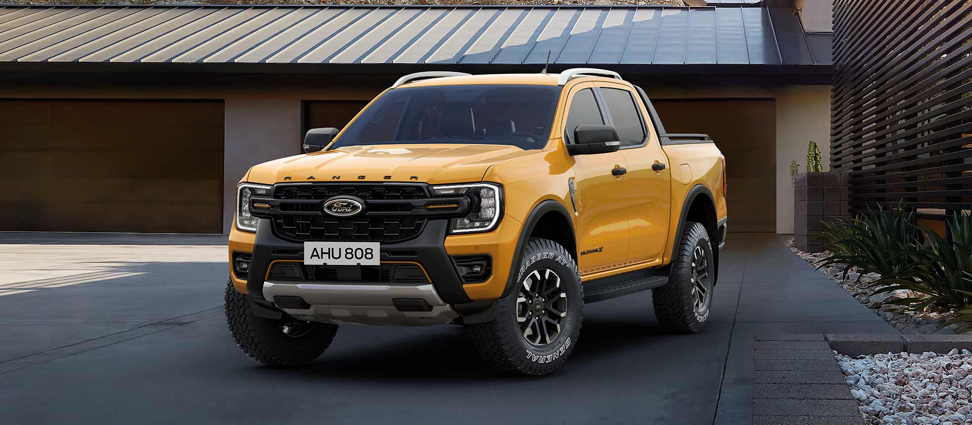 Żółty Ford Ranger z podwójną kabiną zaparkowany przed domem.