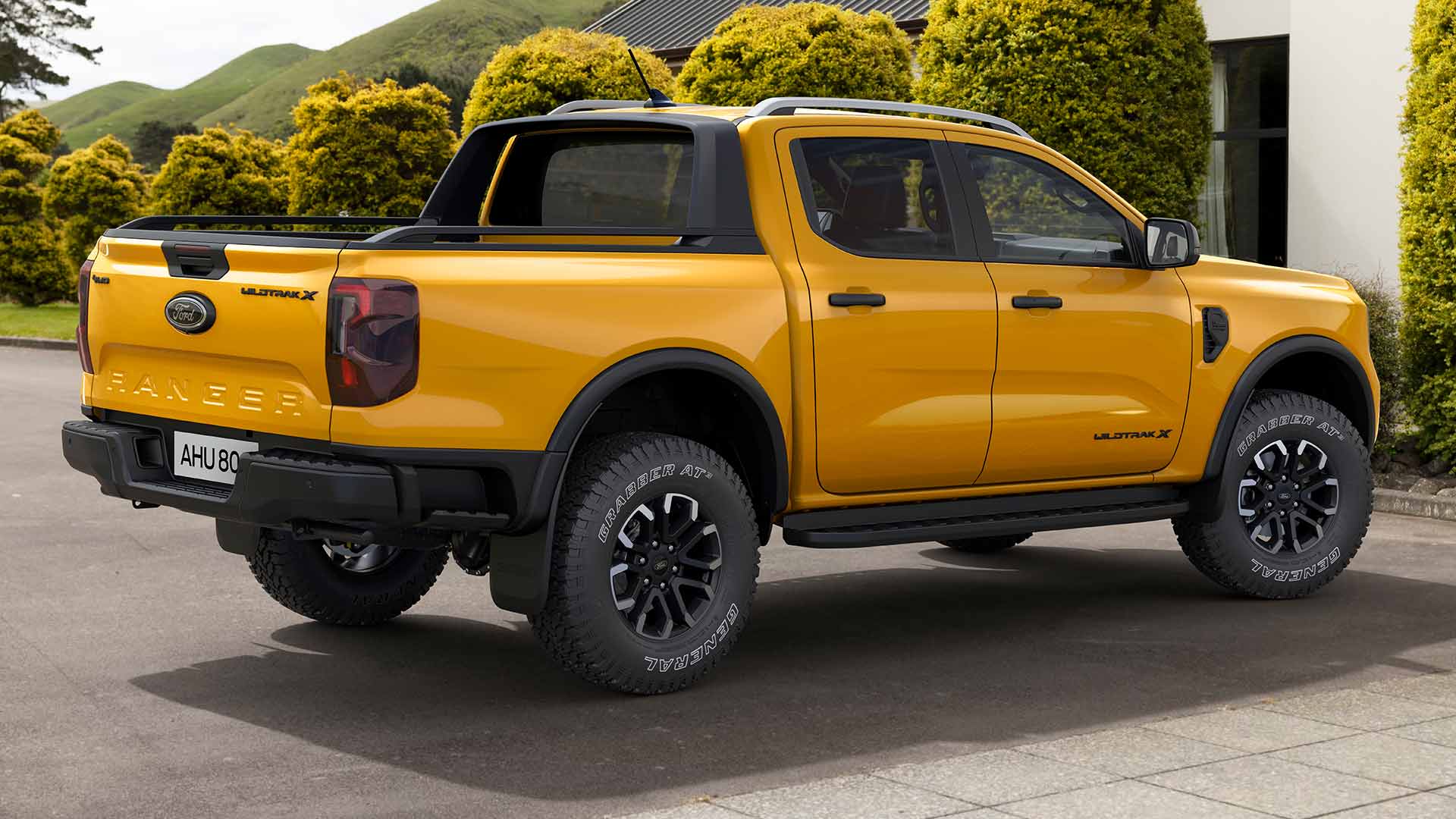 Żółty Ford Ranger z podwójną kabiną zaparkowany na wybrukowanym podjeździe.
