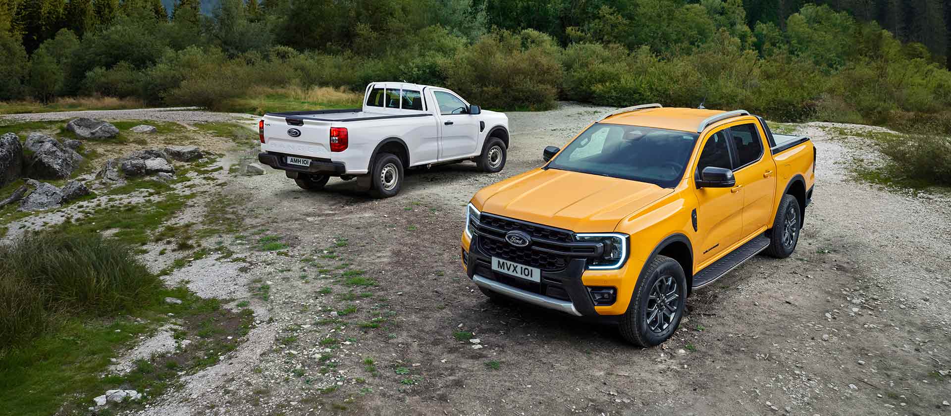 Biały Ford Ranger i żółty Ford Ranger stoją zaparkowane na bocznej drodze.
