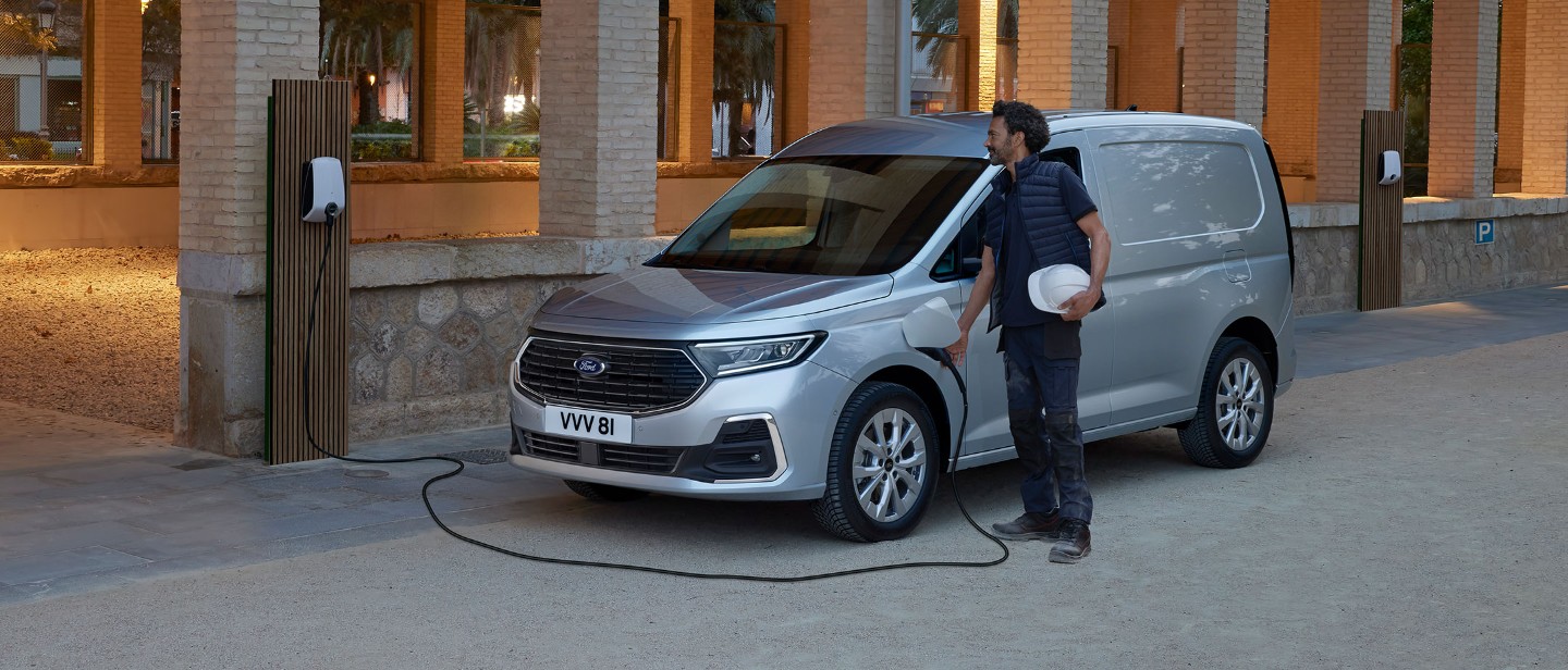 Man charging a Silver Ford Transit Connect whilst parked on the side of the road