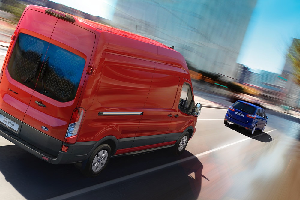 Ford Transit Van w kolorze czerwonym poruszający się po drodze.