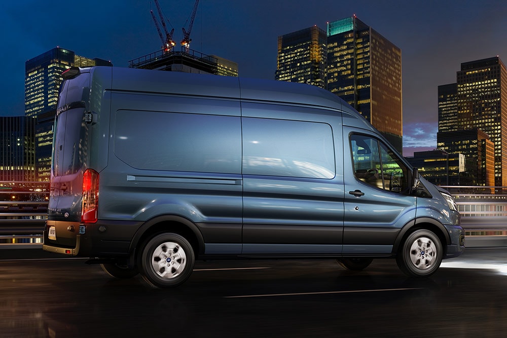 Ford Transit Van przejeżdżający przez miasto nocą.