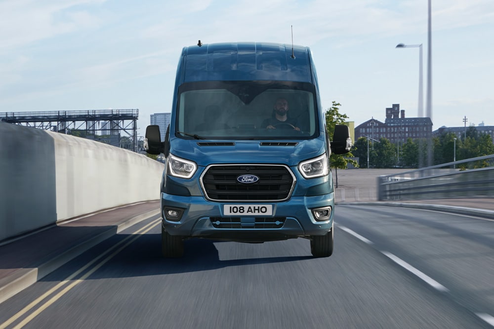 Niebieski Ford Transit Van poruszający się po drodze – widok z przodu.