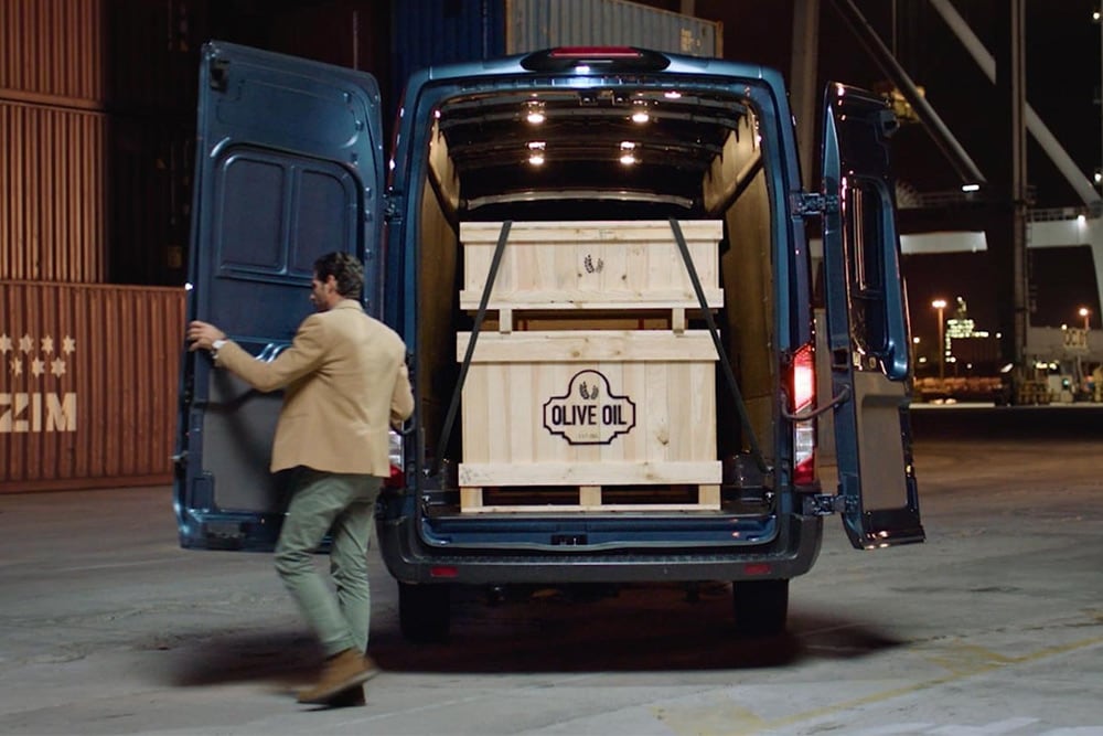 Ford Transit z otwartymi tylnymi drzwiami i widocznym ładunkiem.