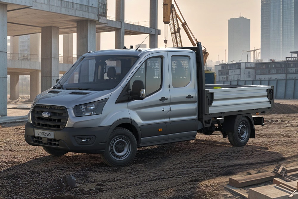 Ford Transit typu podwozie z podwójną kabiną zaparkowany na placu budowy.