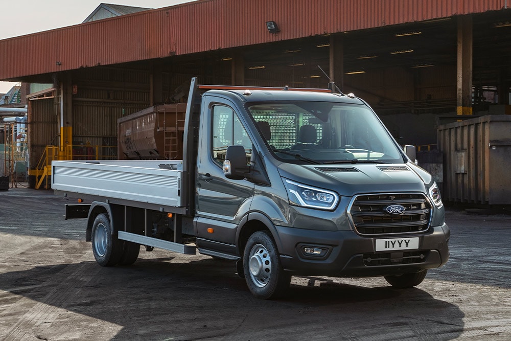 Ford Transit typu podwozie z kabiną zaparkowany na terenie przemysłowym.