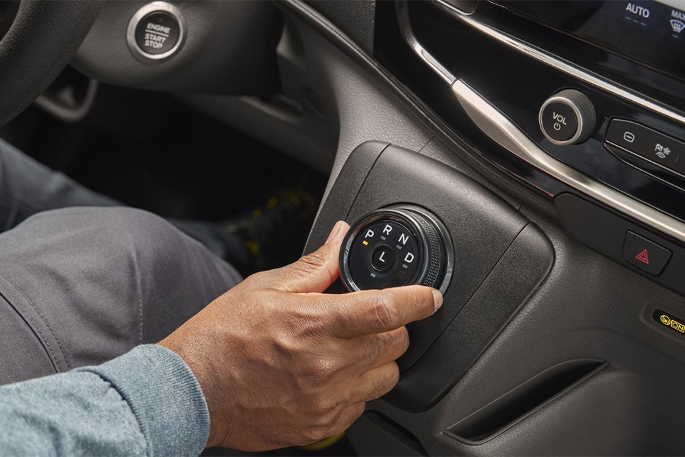 Close-up of a hand operating the rotary gear selector in a Ford Transit Minibus.