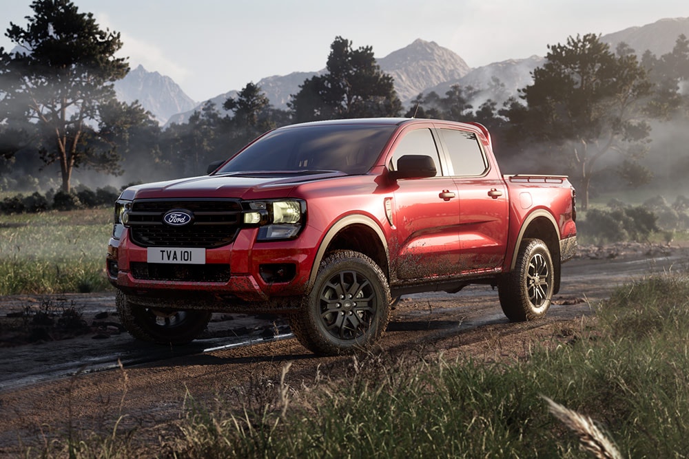 Czerwony Ford Ranger Raptor wznosi tumany kurzu, przejeżdżając przez malowniczy atrakcyjny krajobraz.