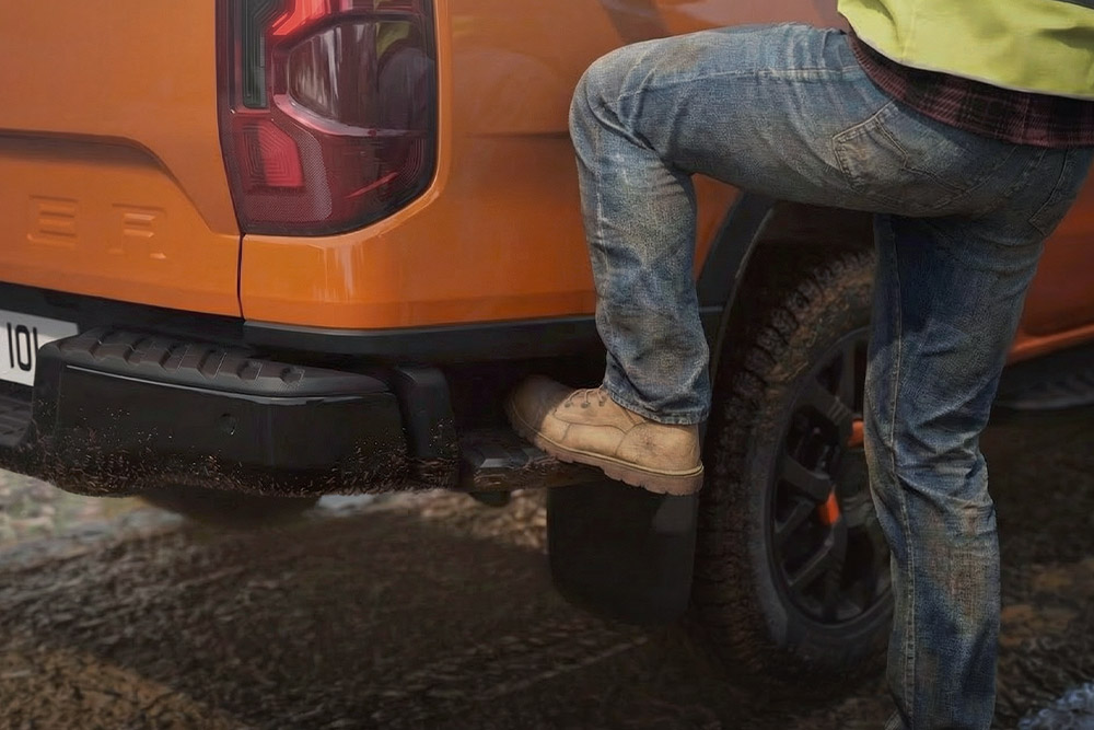 Pracownik wchodzący na zintegrowany tylny stopień Forda Ranger Wildtrak.