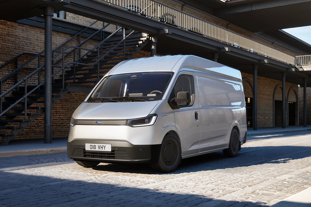 Srebrny van Ford Transit City® L2H2 zaparkowany przed ceglanym budynkiem.