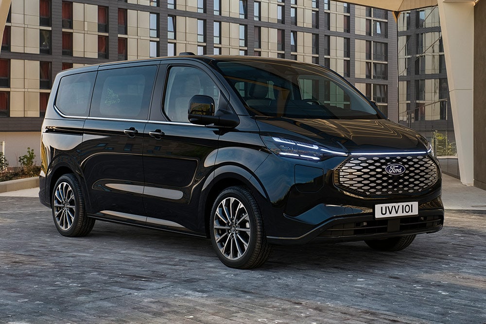  Czarny Ford Pro Transit zaparkowany przed nowoczesnym budynkiem.