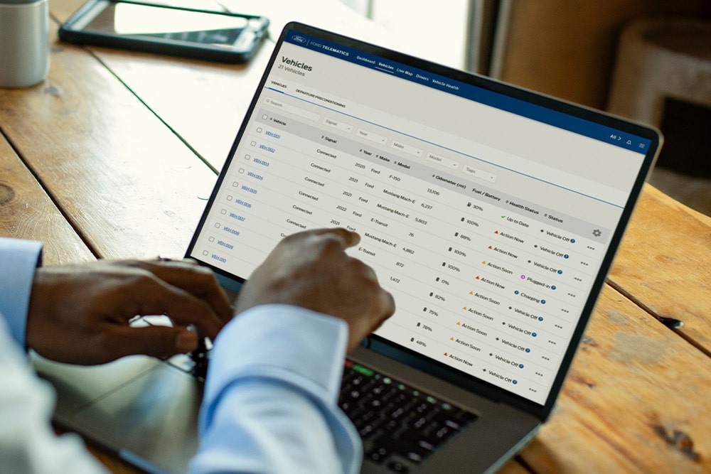  Menedżer floty Ford Pro przeglądający dane pojazdu na swoim laptopie.