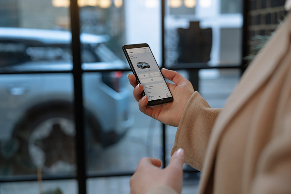 Osoba trzymająca smartfon, na którym widać aplikację FordPass z informacjami dotyczącymi zarządzania flotą.